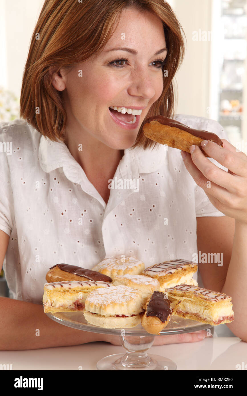 WOMAN EATING FRESH CREAM CAKES Stock Photo