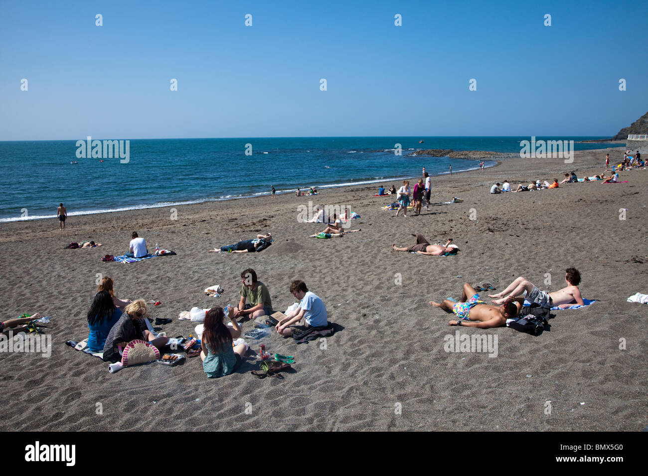 Students sunbathing on beach Aberystwyth Wales UK Stock Photo