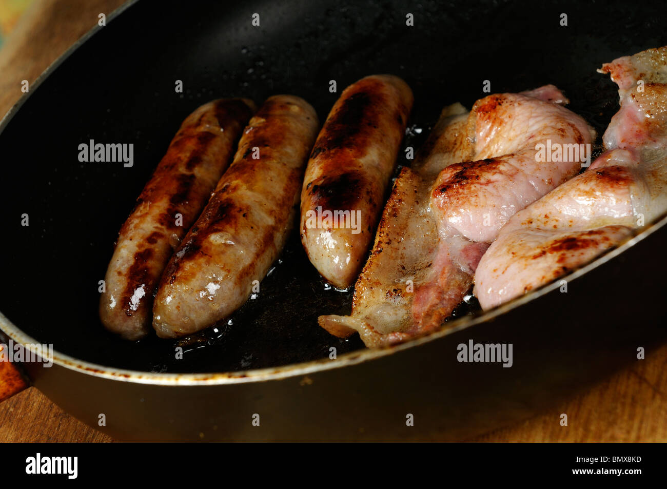 Stock photo of bacon and sausages cooking in a frying pan. Stock Photo