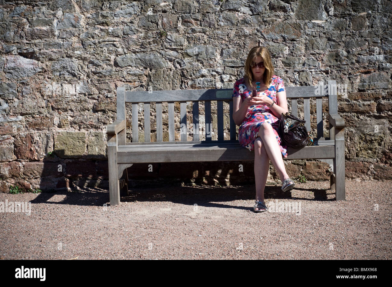Women texting on park bench Stock Photo
