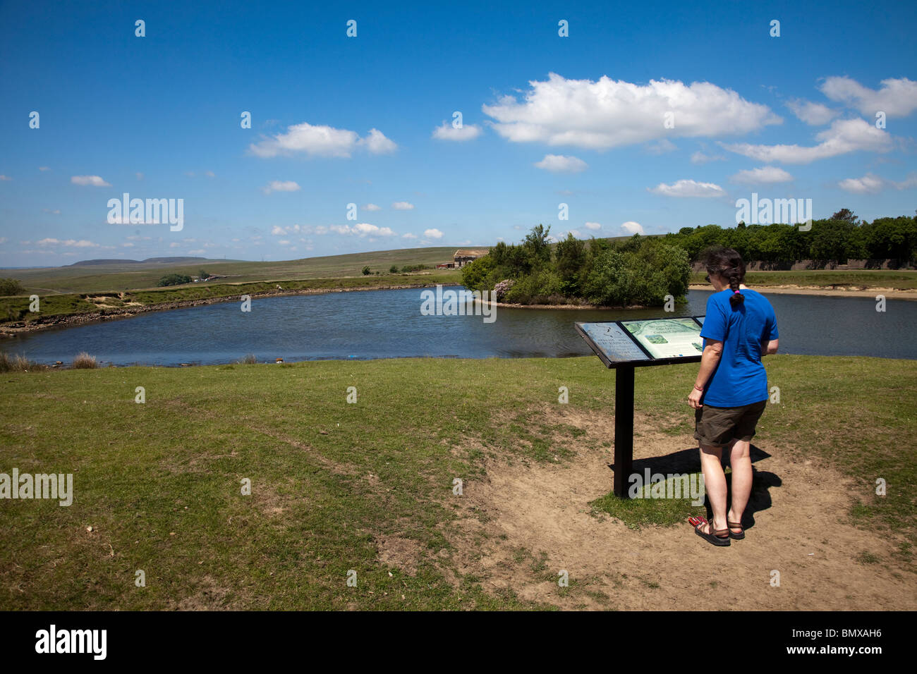 Person reading information sign at pond built around 1800 to supply water to Tredegar Ironworks Wales UK Stock Photo
