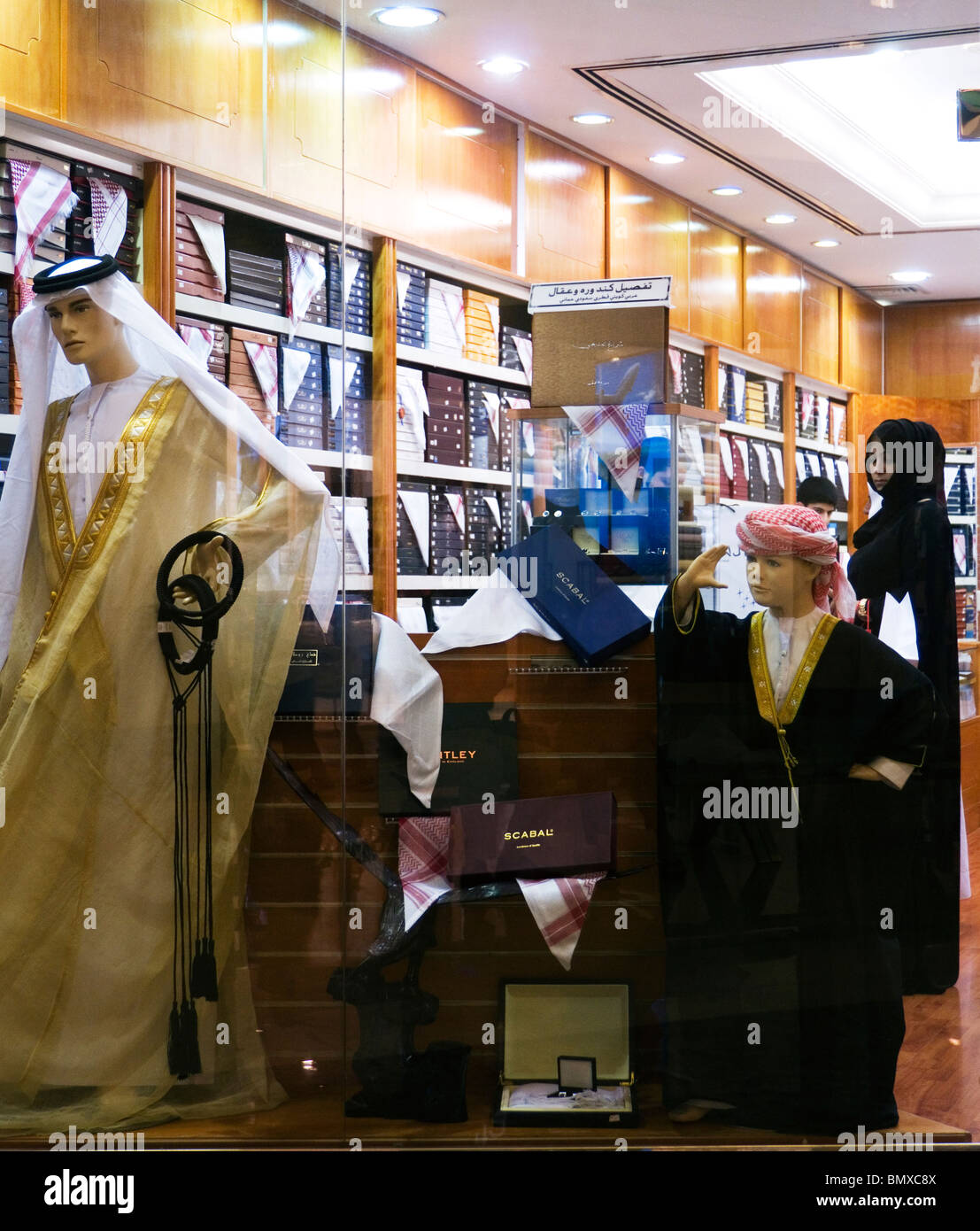 Woman shopper in a menswear store selling Gulf Arab national dress at the Abu Dhabi Mall, Abu Dhabi Stock Photo