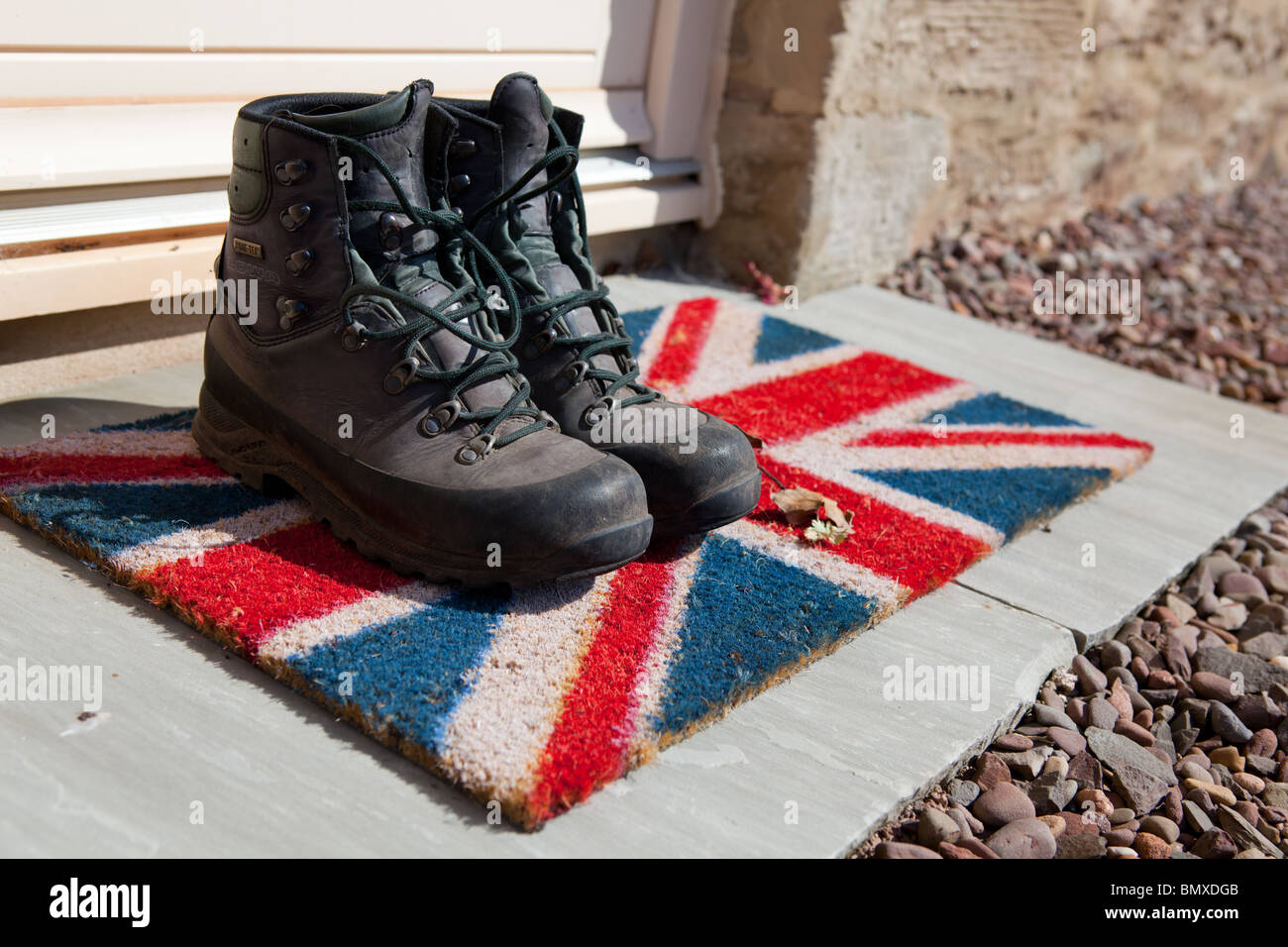 A Pair Of Well Used Walking Boots On A Union Jack Doormat