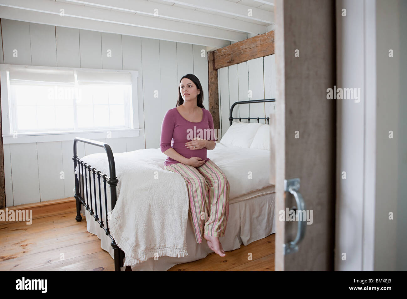Expectant mother sitting on bed Stock Photo