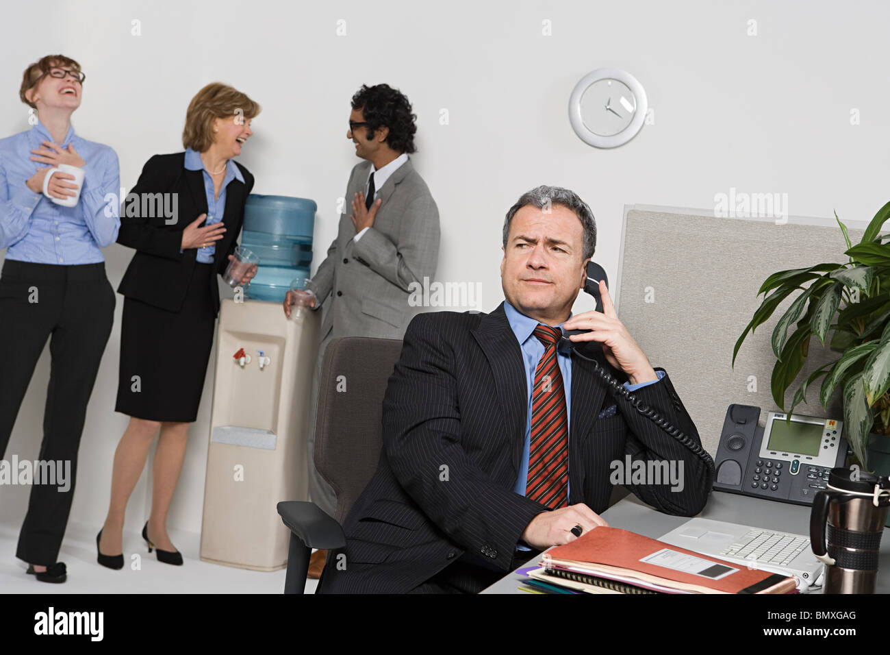 Businessman On Telephone With People Gossiping By Water Cooler Stock Photo Alamy