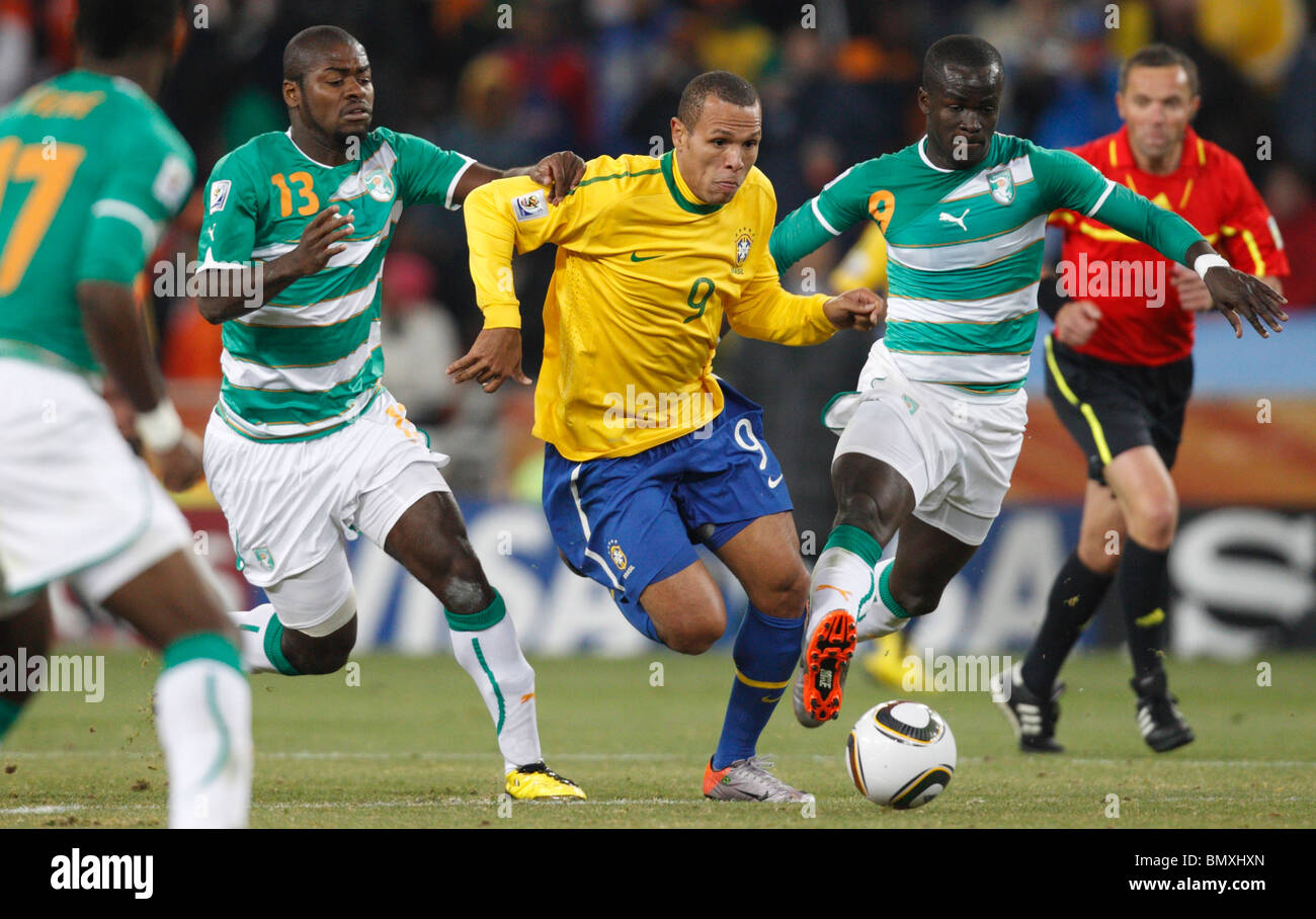 Luis Fabiano of Brazil (c) fights past Romaric (l) and Ismael Tiote (r) of Côte d'Ivoire during a 2010 World Cup football match. Stock Photo