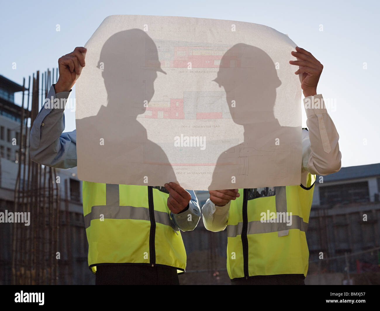 Mature men inspecting blueprints on construction site Stock Photo