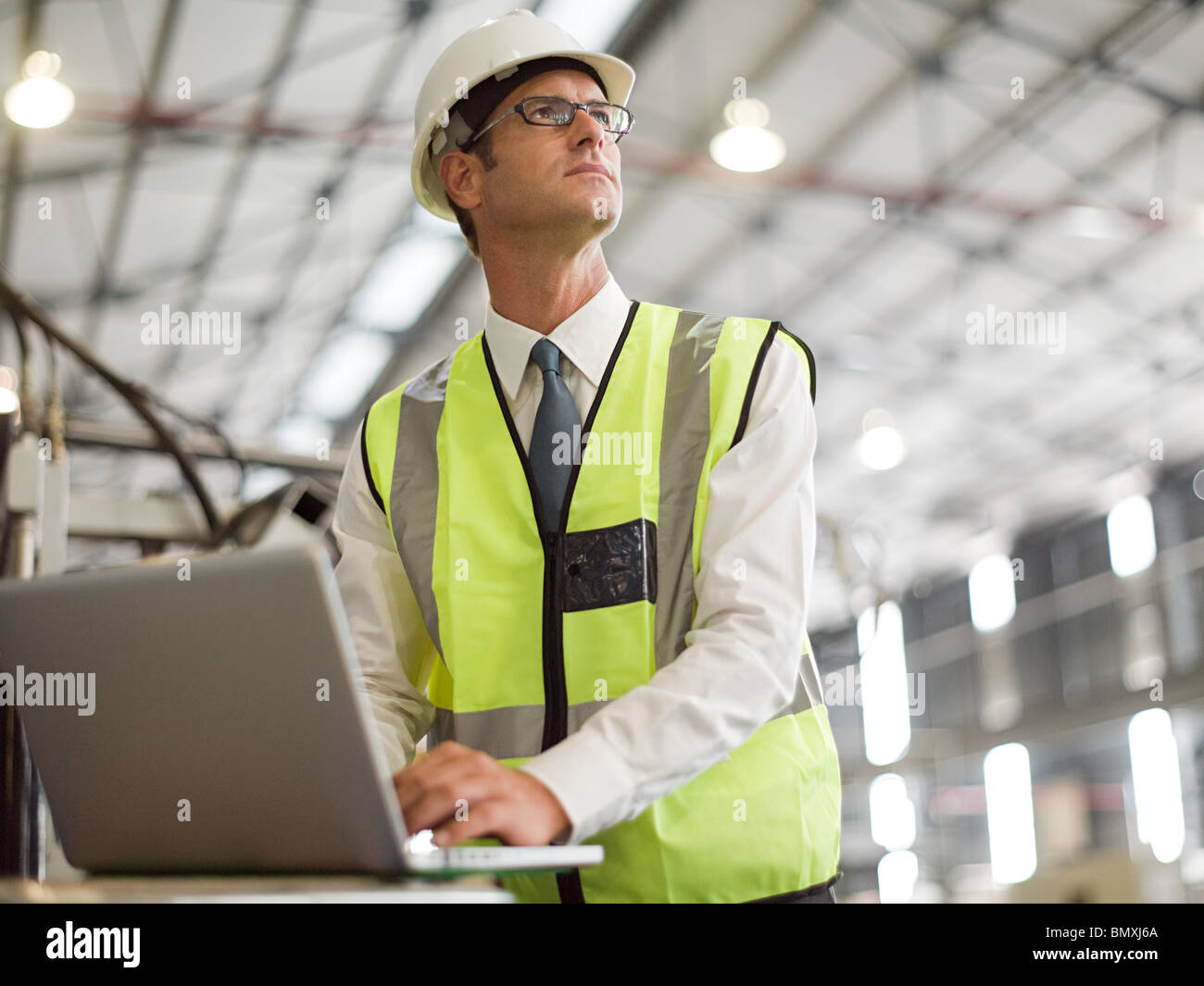 Mature man using laptop in factory Stock Photo