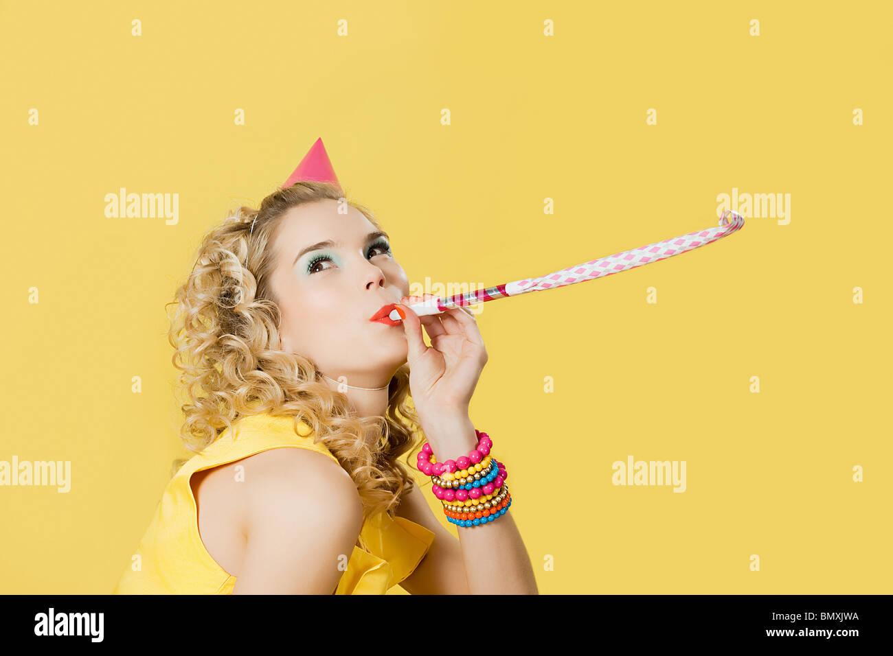 Young woman wearing party hat with party blower Stock Photo - Alamy