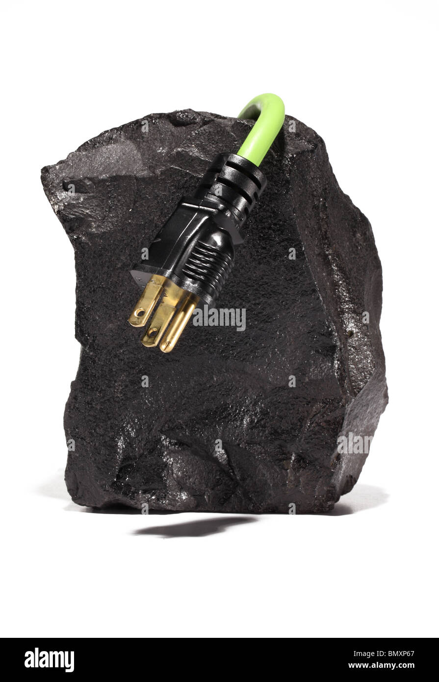 A large black piece of coal with a green electrical extension cord and plug wrapping around on a white background. Stock Photo