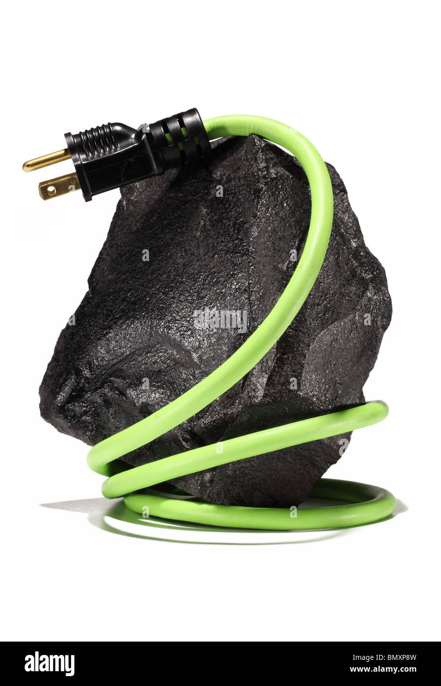 A large black piece of coal with a green electrical extension cord and plug wrapping around on a white background. Stock Photo