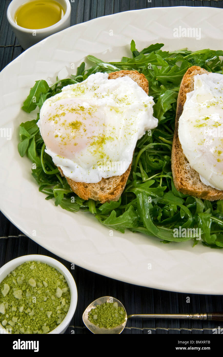 Poached eggs and Matcha japanise tea salt in a arugola (rocket, eruca sativa, rucola) bed Stock Photo