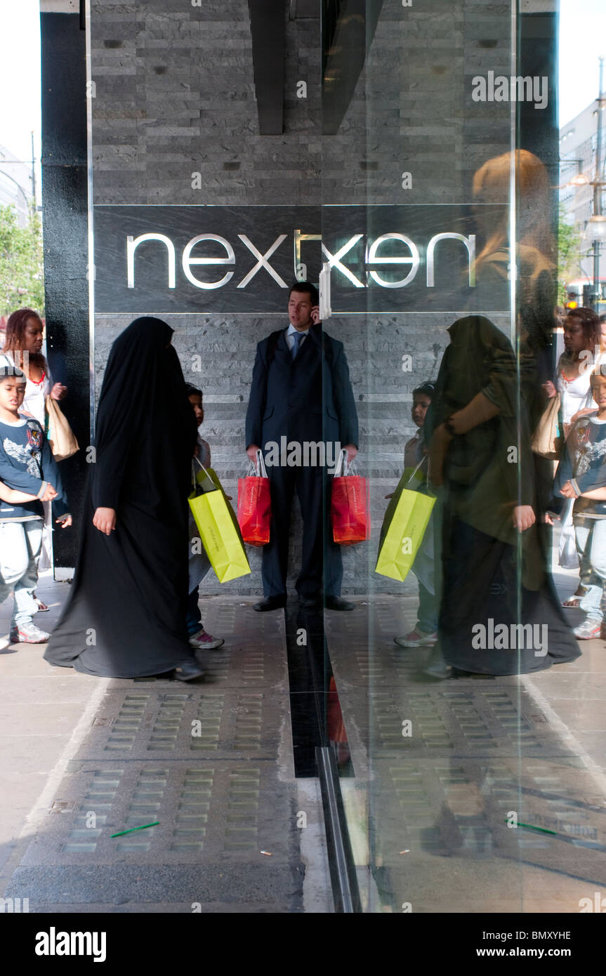 Man with red carrier bag in front of Next store on Oxford Street, London, UK Stock Photo