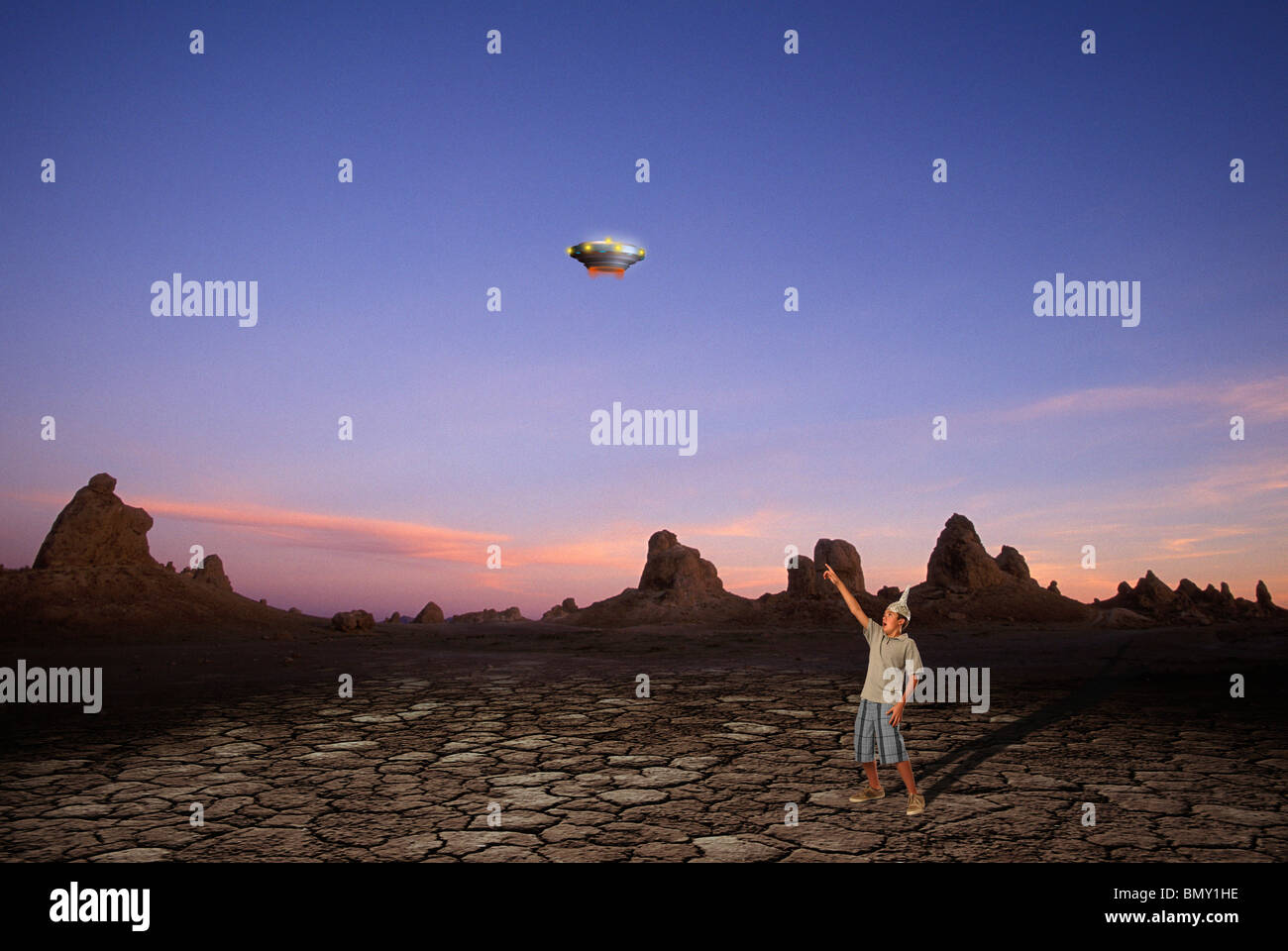 Boy wearing tinfoil hat pointing to UFO in desert sky Stock Photo Alamy