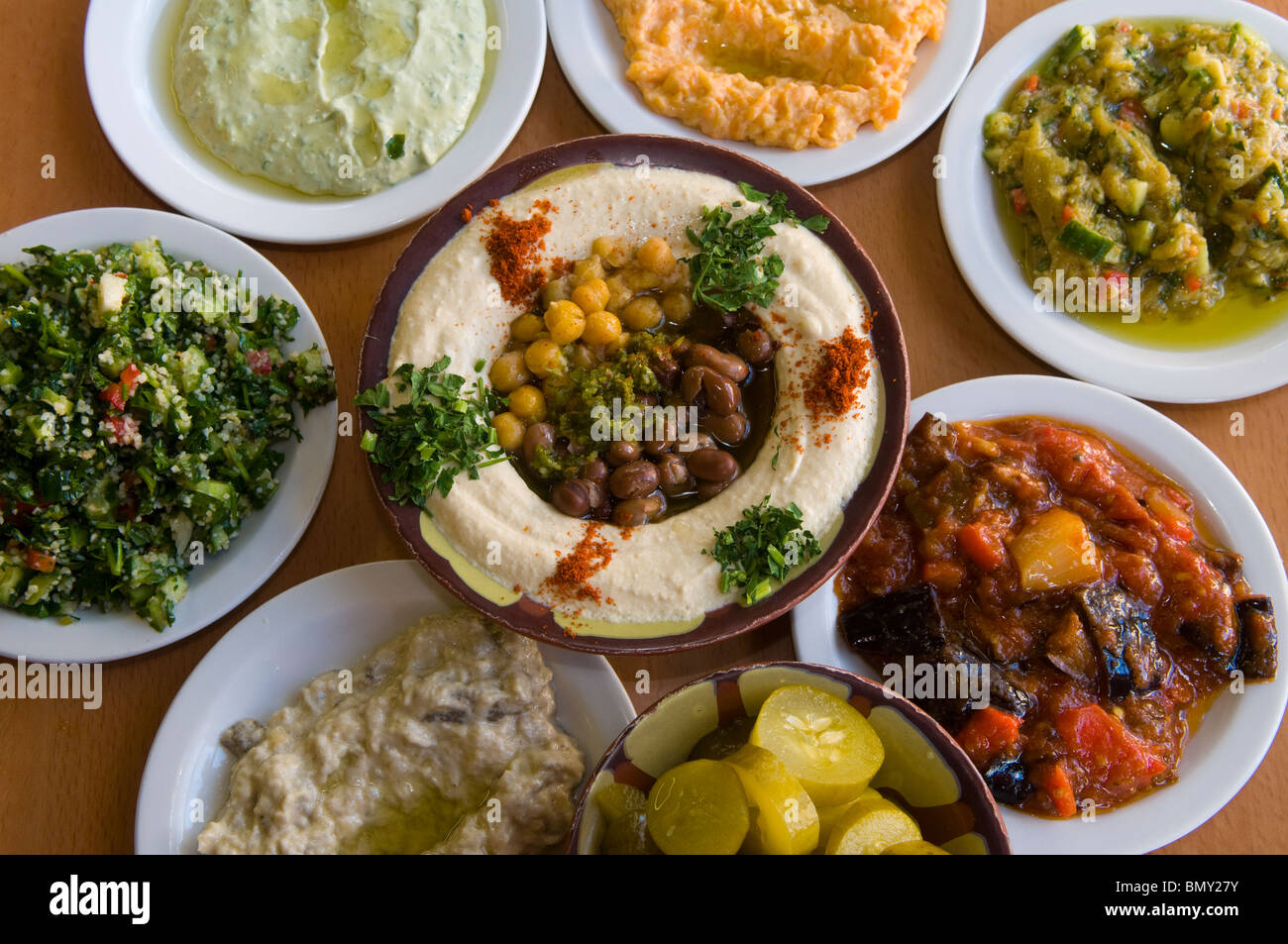 Plate of Hummus with Ful or Foul brown fava beans with all sort of Mediterranean typical mezze salads served in a restaurant Israel Stock Photo