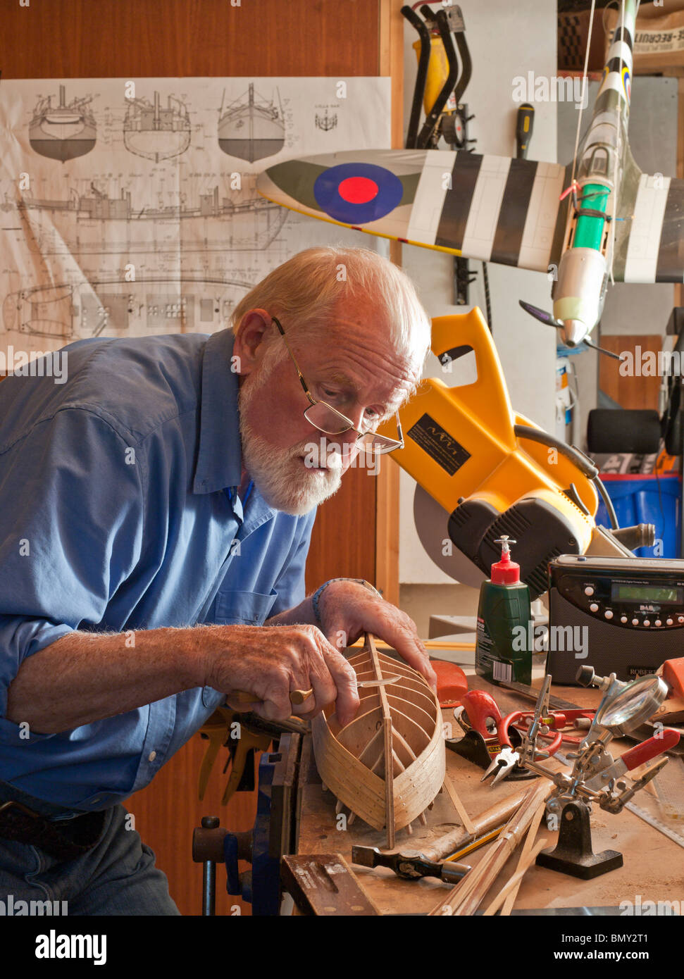 Older man, retiree, making model boat in workshop. UK Stock Photo