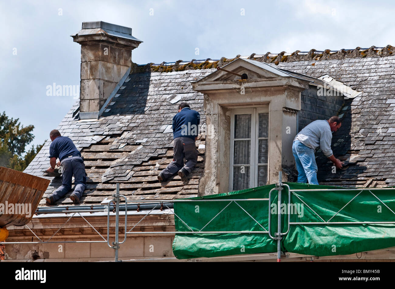 Workers on town house roof removing old slates / no safety