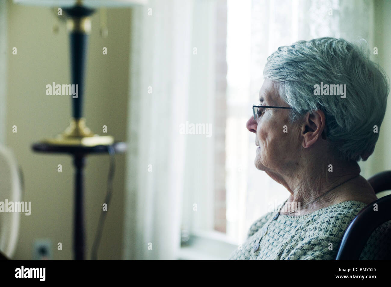 Profile of old woman sitting in chair, looking straight ahead. Stock Photo