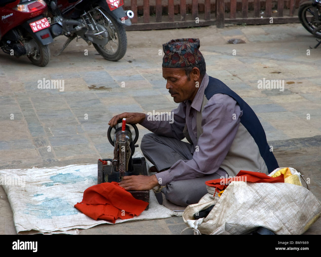 An friendly old man with his sewing machine does mending and sewing on the street at Durbar