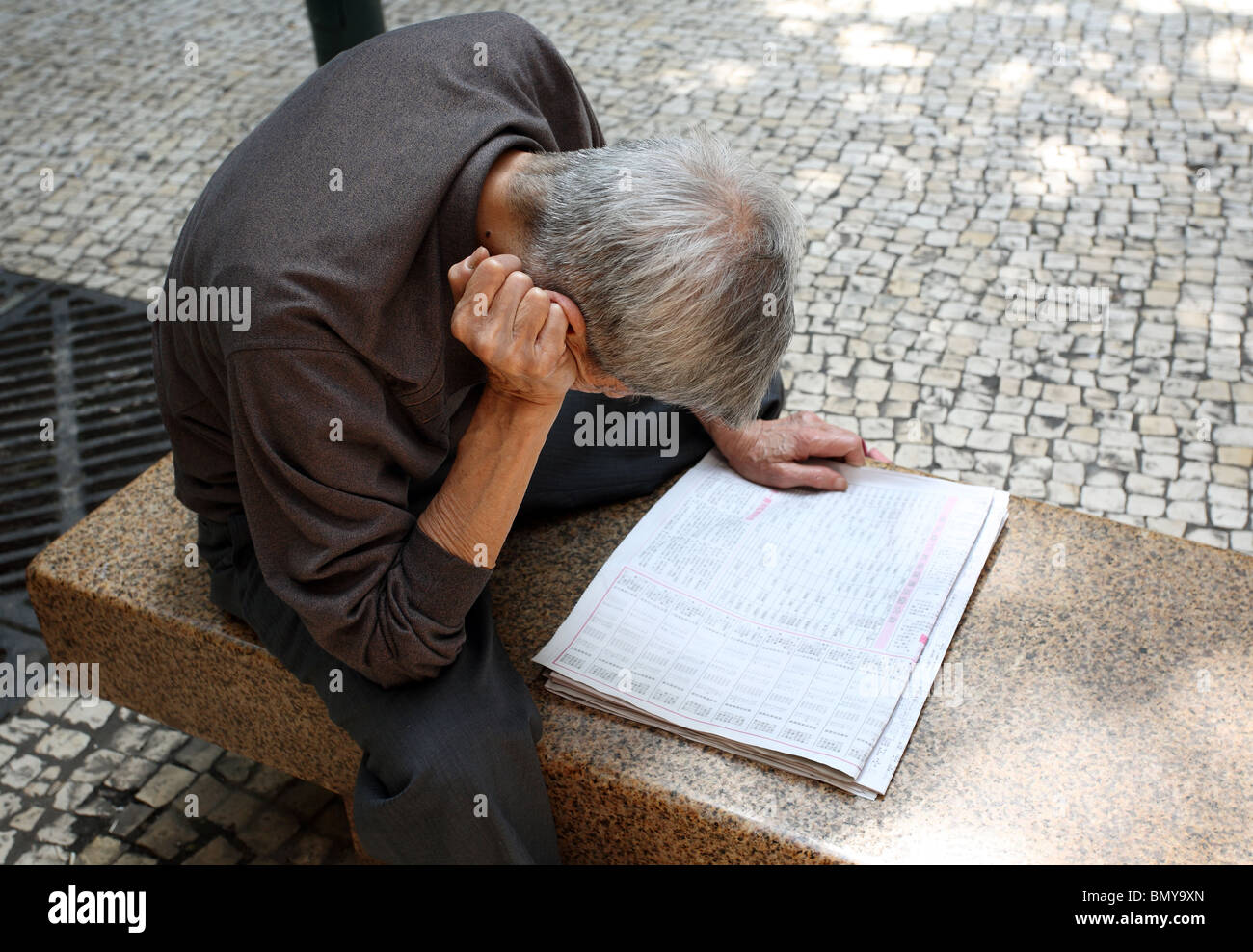 A man reading a newspaper, Macao, China Stock Photo