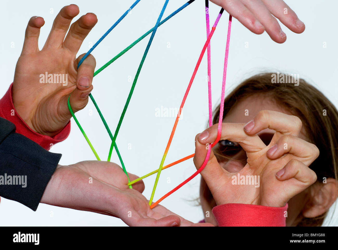 Hands of 2 girls playing fingertwist with a coulored rope. Stock Photo
