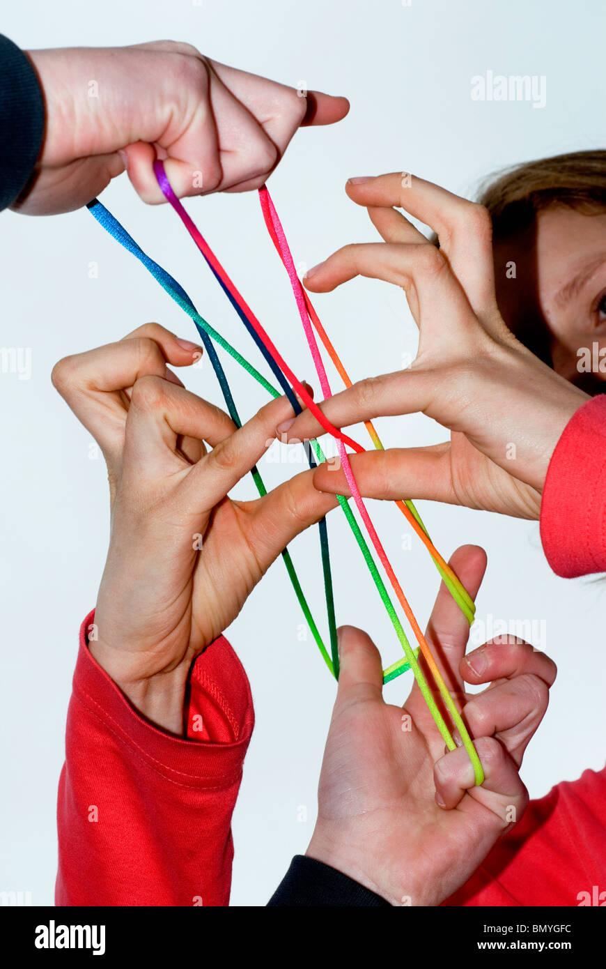Hands of 2 girls playing fingertwist with a coulored rope. Stock Photo