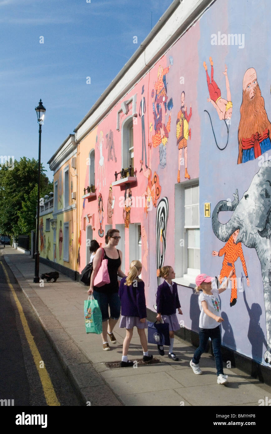 Chelsea Arts Club London UK. Family mother children walking to school past the redecoration their private club building in Old Church Street Chelsea London. Art work murals by Tony Common. Temporary wall mural  2010 2010s England HOMER SYKES Stock Photo