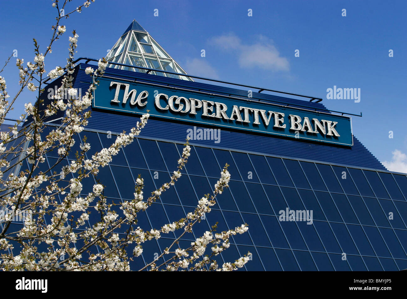 England, Cheshire, Stockport, Co-Operative Bank pyramid in spring with tree in blossom Stock Photo