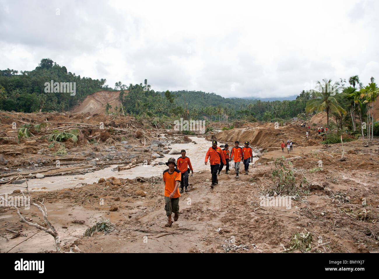Rescue workers walk through the rubble of a landslide triggered by the earthquake, in Padang Pariaman, West Sumatra, Indonesia Stock Photo