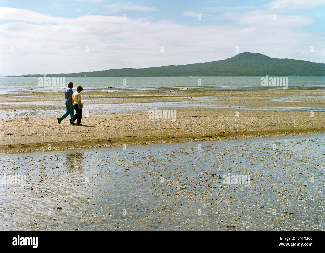 Couple walking on St Heliers Bay beach Auckland New Zealand Stock Photo