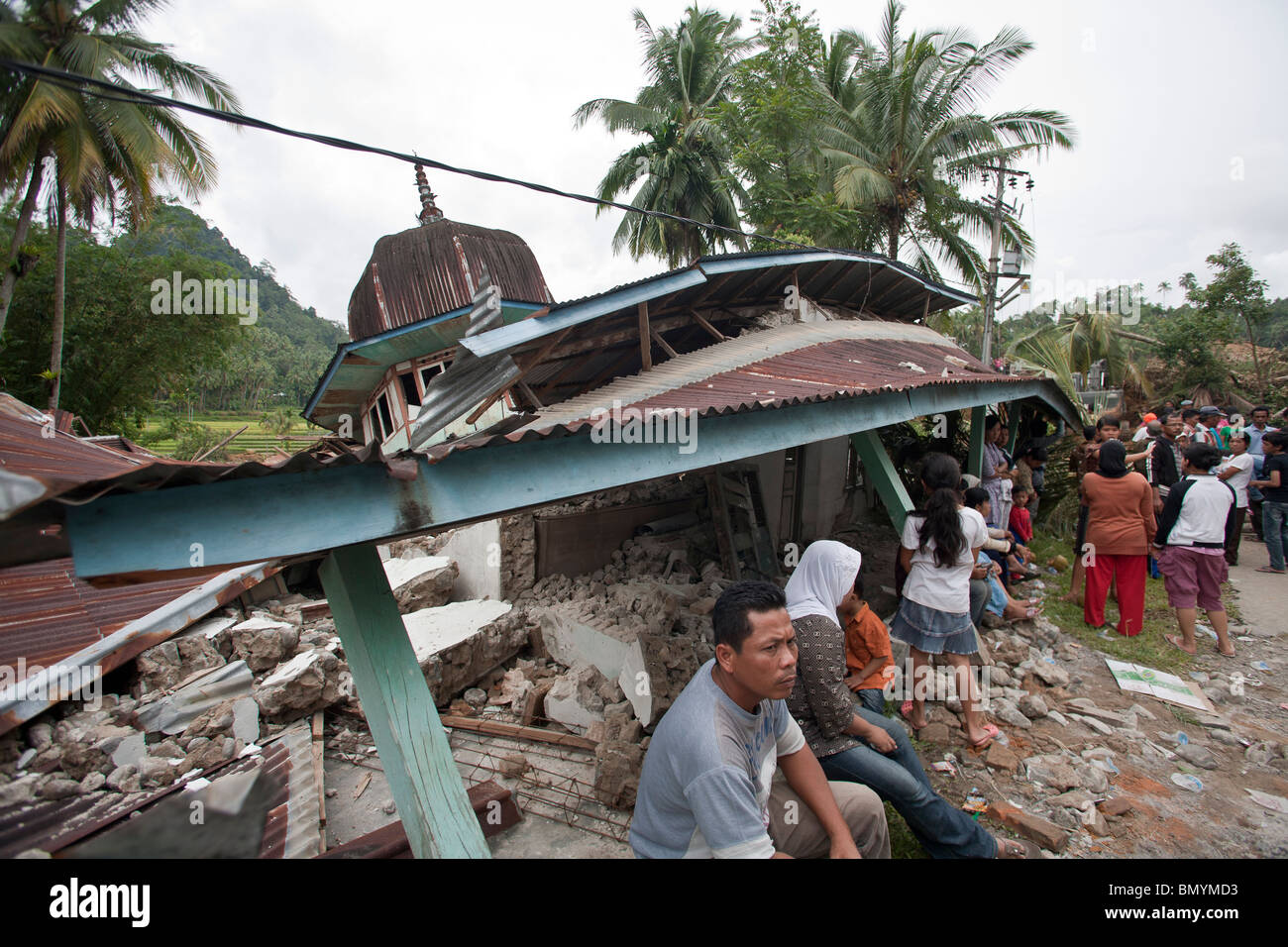 Villagers sit by a mosque damaged by the earthquake in Padang Pariaman, West Sumatra, Indonesia, Stock Photo