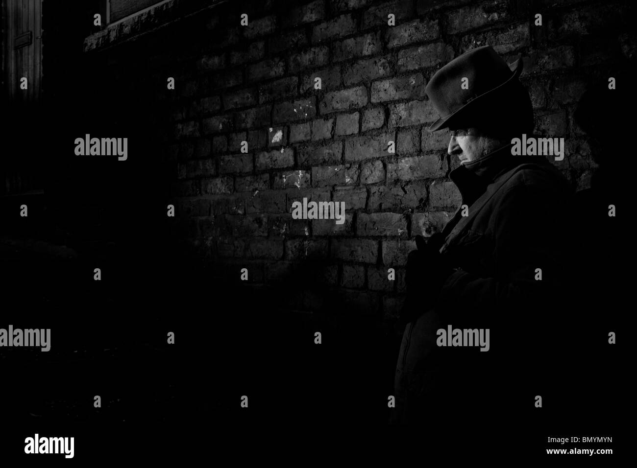Film Noir depicting a quiet and dangerous man waiting in a darkened alley. Stock Photo