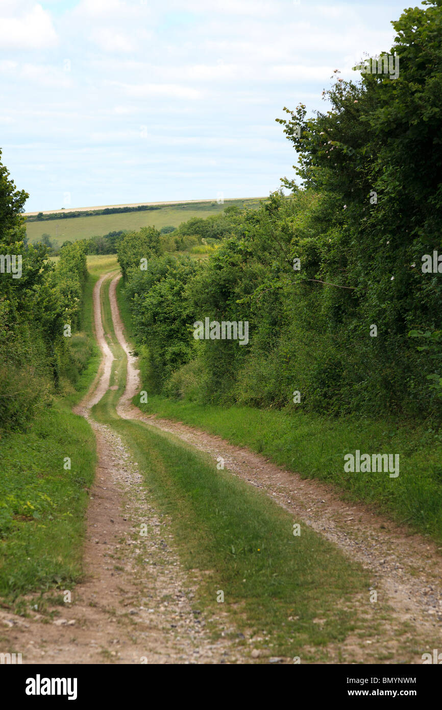 countryside farm dirt track down and up hill into the distance Stock Photo