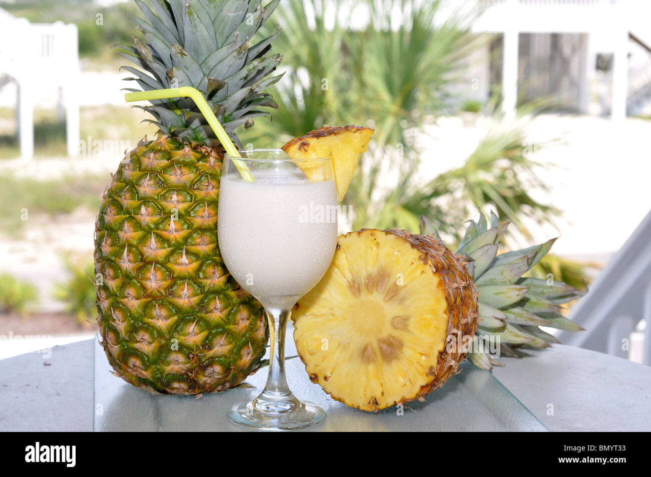 Pina Colada on table with whole and half pineapple. Garnish and straw in glass. Stock Photo