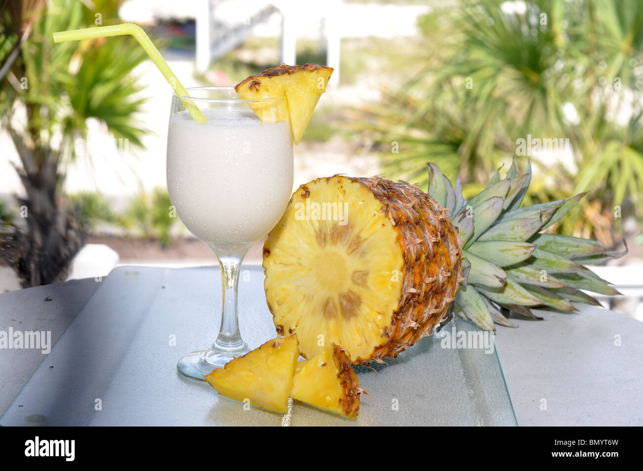 Pina Colada on table with pineapple half and slices. Garnish and straw in glass. Stock Photo