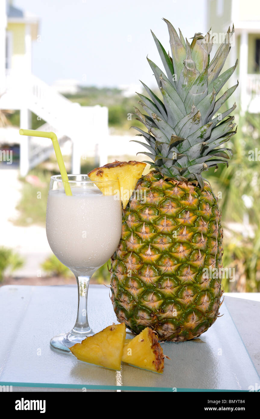 Pina Colada on table with whole pineapple and slices. Garnish and straw in glass. Stock Photo
