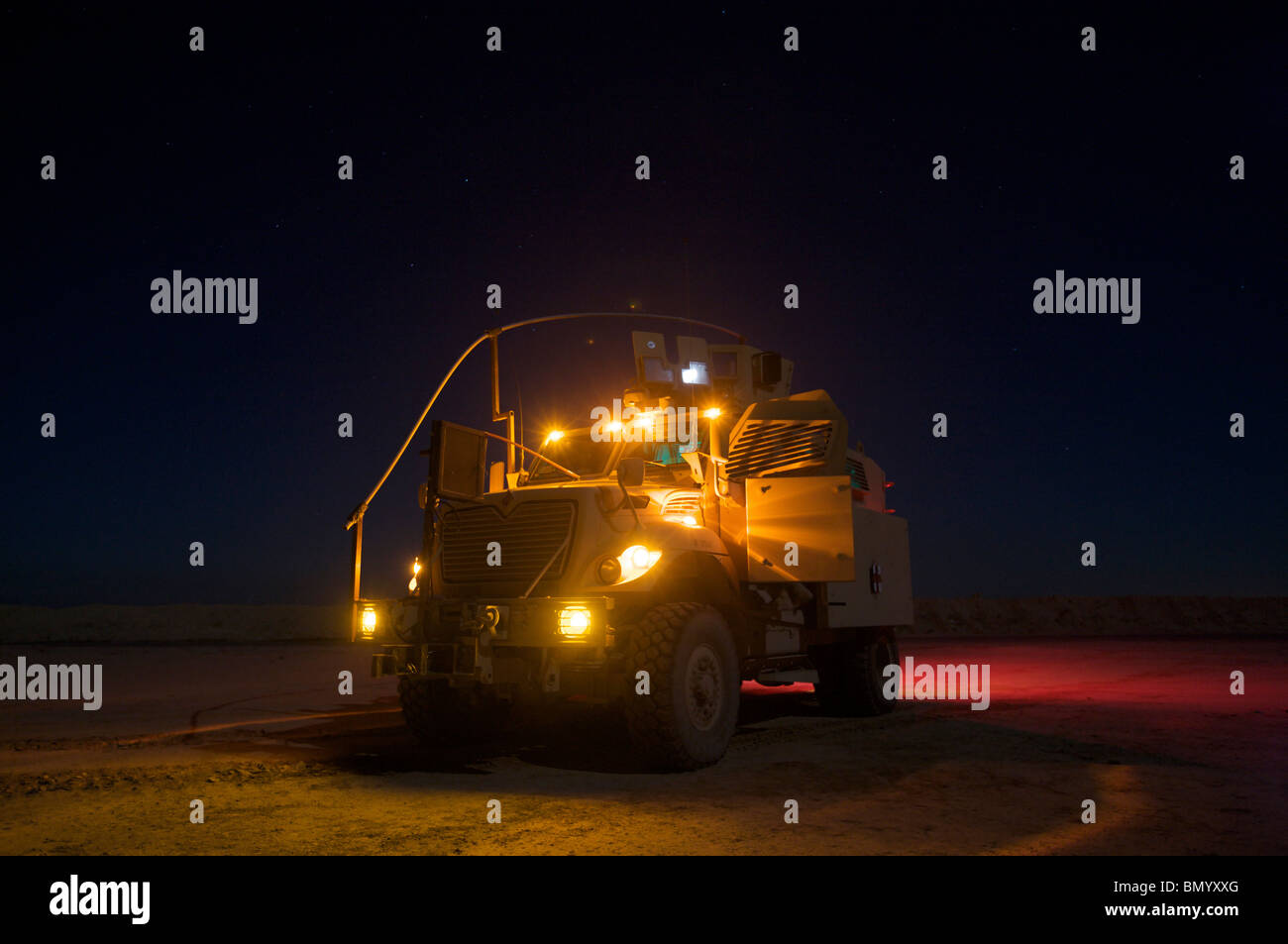 A MaxxPro Mine Resistant Ambush Protected (MRAP) vehicle with running lights on at night. Stock Photo