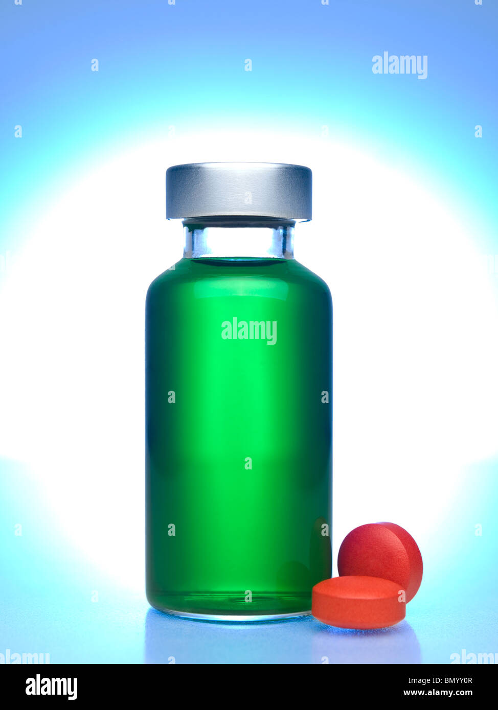 Close up of a vial full of green liquid, red pills aside. Stock Photo