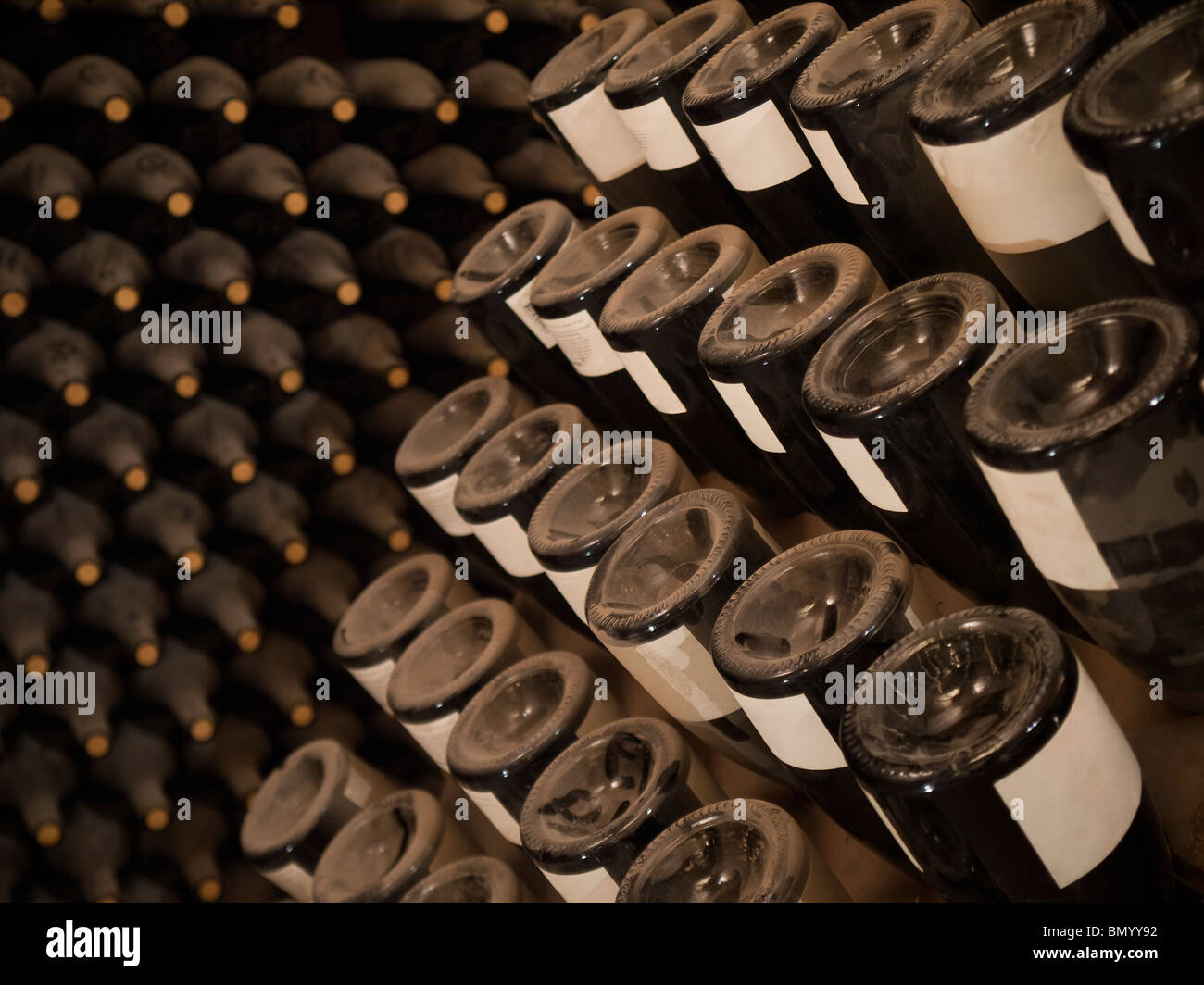 Upside down wine bottles in a rack. More bottles on the background