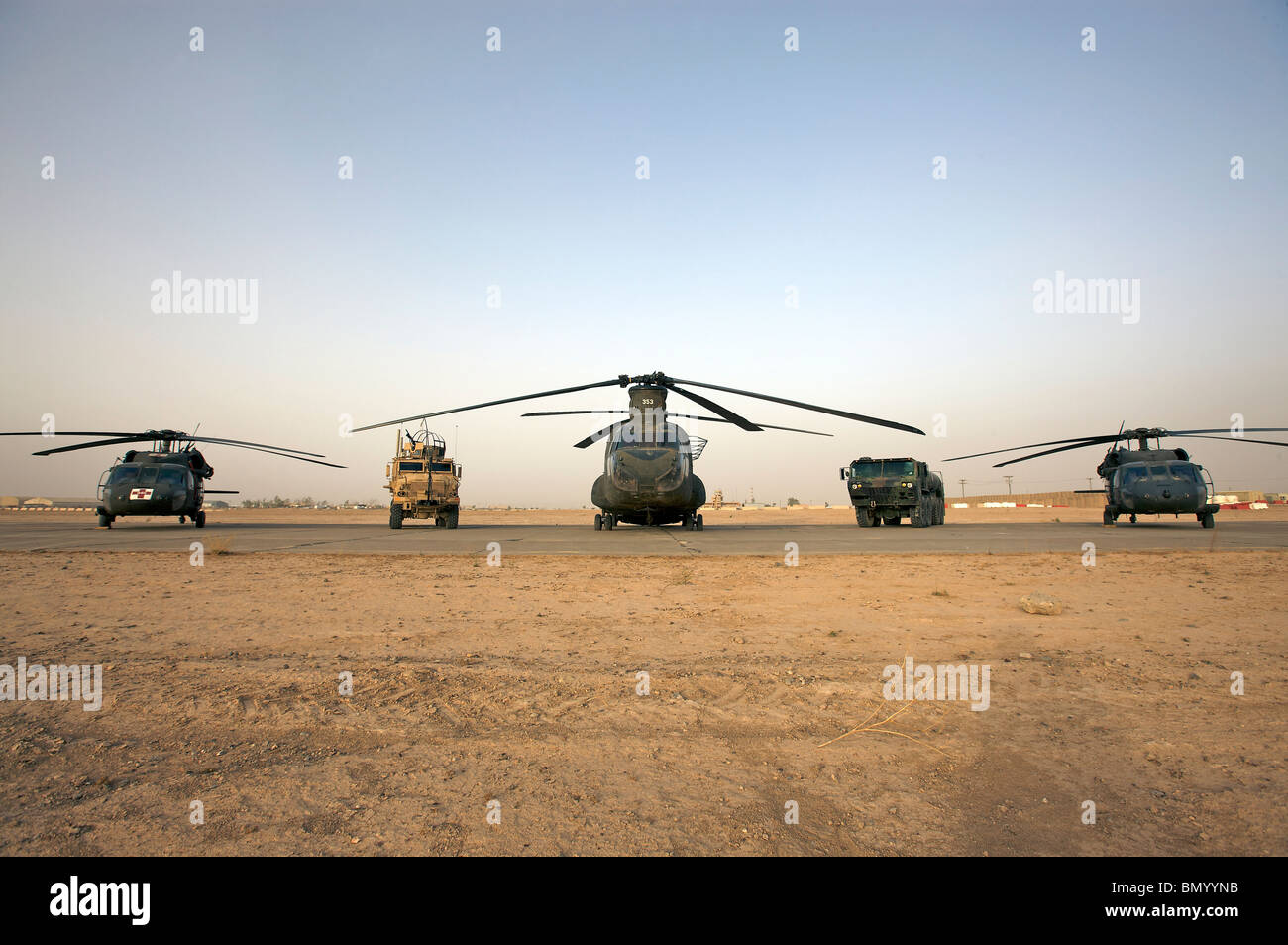 U.S. military vehicles and aircraft lined up on the taxiway at Camp Speicher, Iraq. Stock Photo