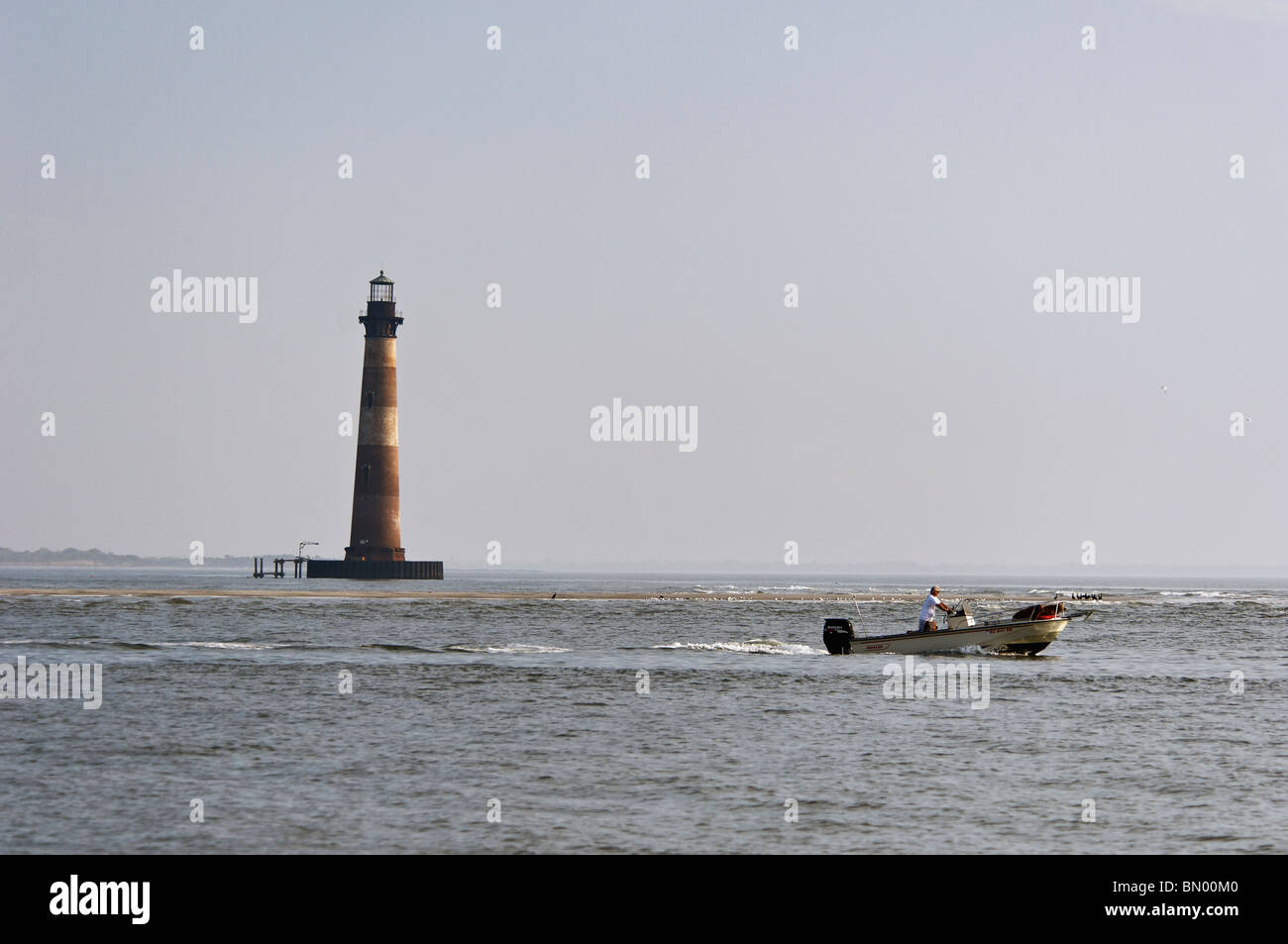 Man in Boston Whaler Motoring Past Morris Island Lighthouse in Charleston County, South Carolina Stock Photo