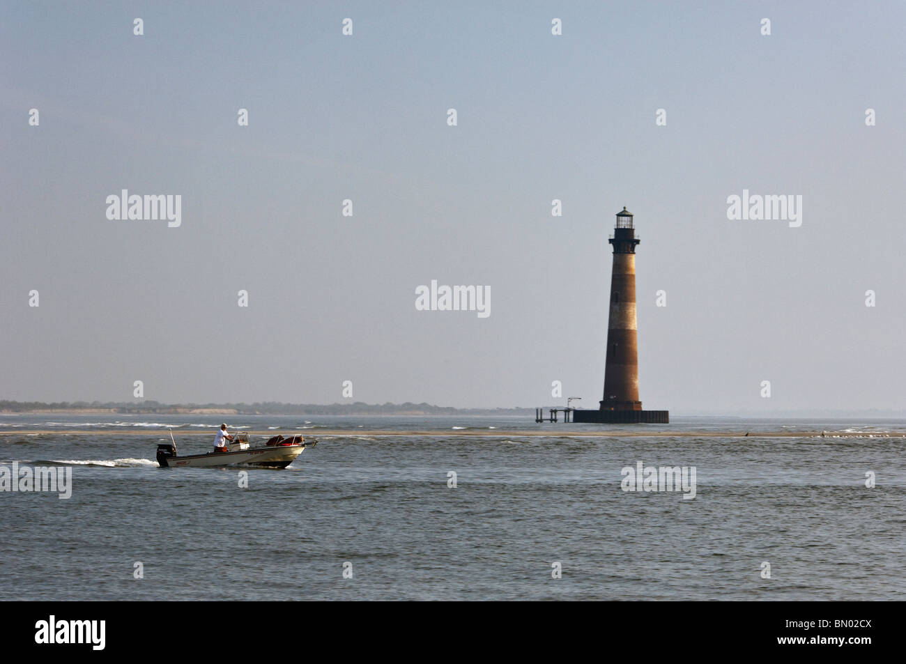 Man in Boston Whaler Motoring Past Morris Island Lighthouse in Charleston County, South Carolina Stock Photo
