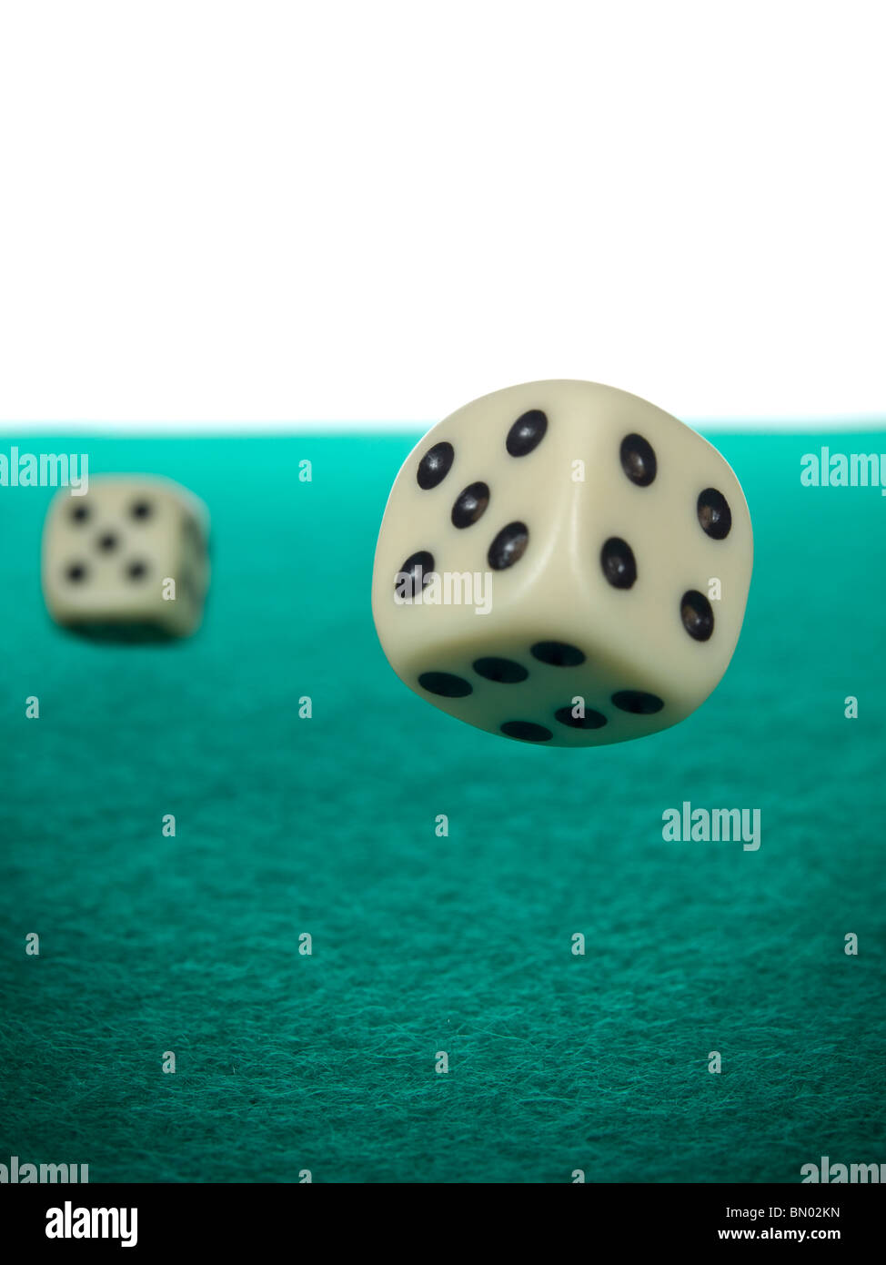 A pair of dices rolling over a green felt. Stock Photo