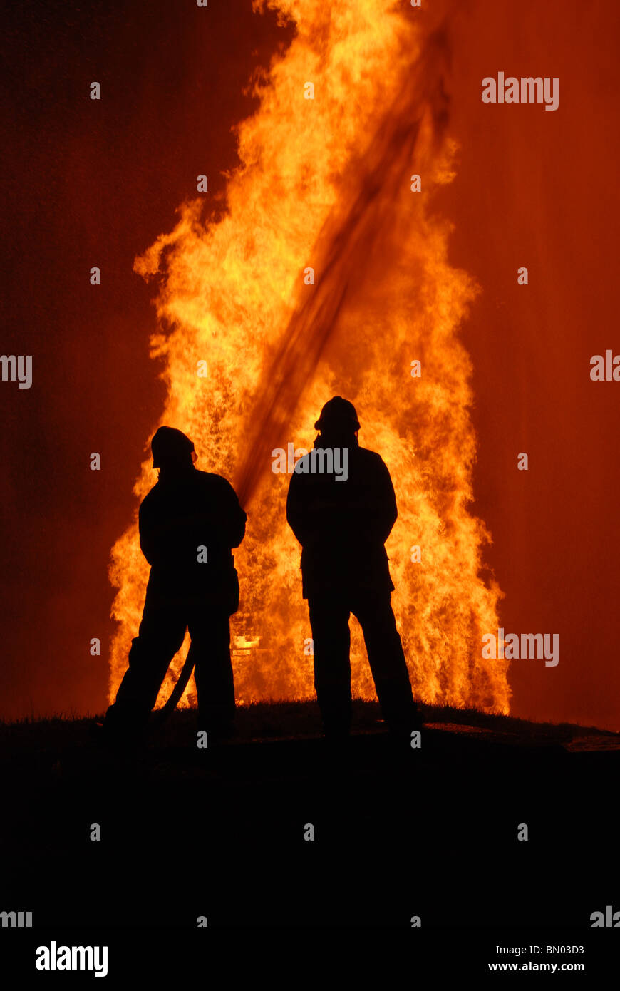 two firemen battling against raging fire, NOTE: top left corner ...