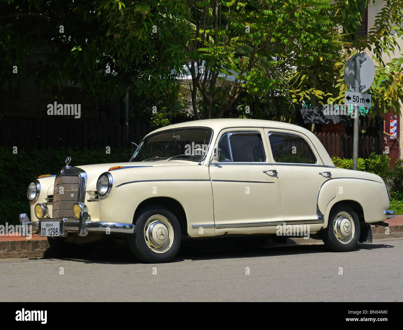 Vintage ivory Mercedes Benz 190 car on the street in Luang Prabang, Northern Laos Stock Photo