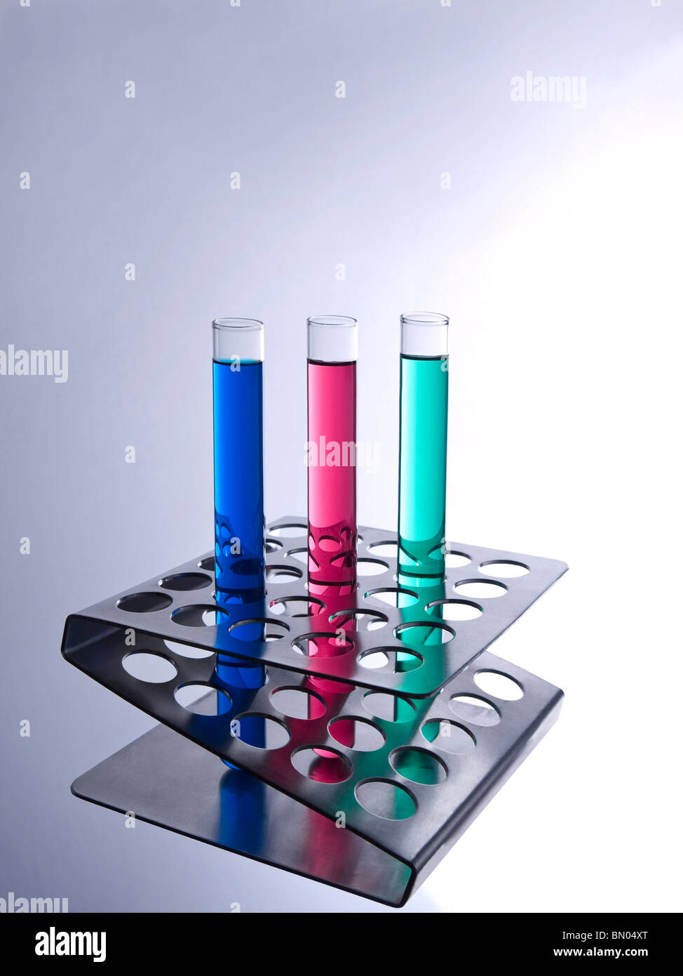 Three test tubes filled with colored liquids on a metallic rack. Stock Photo