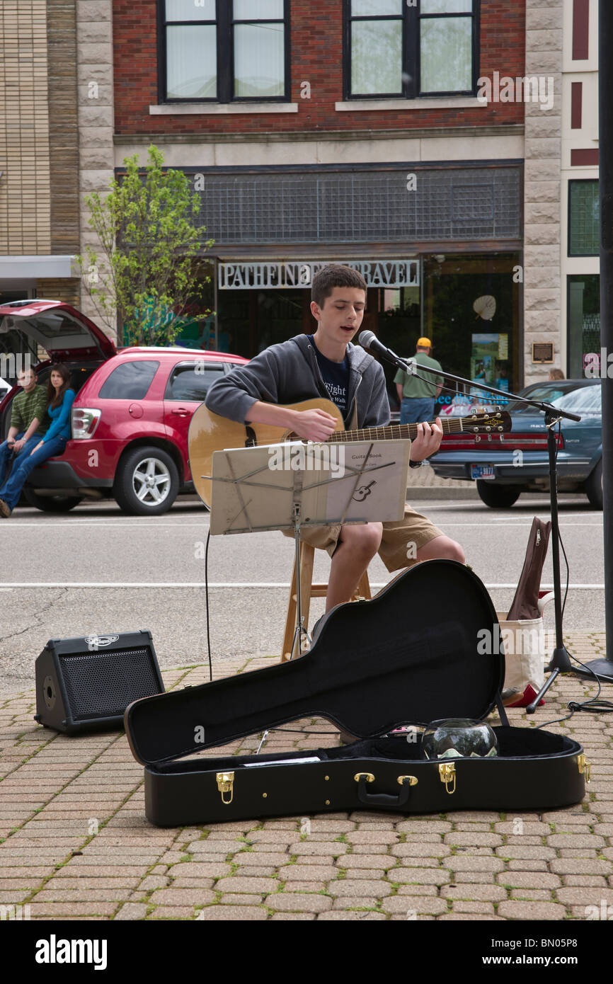 A street performer young man playing on a acoustic guitar on the city ...