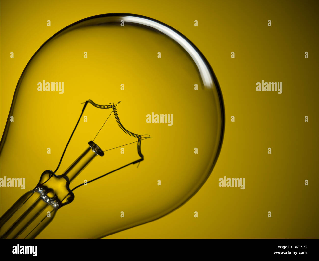 Close up on a transparent light bulb over a yellow background. Stock Photo