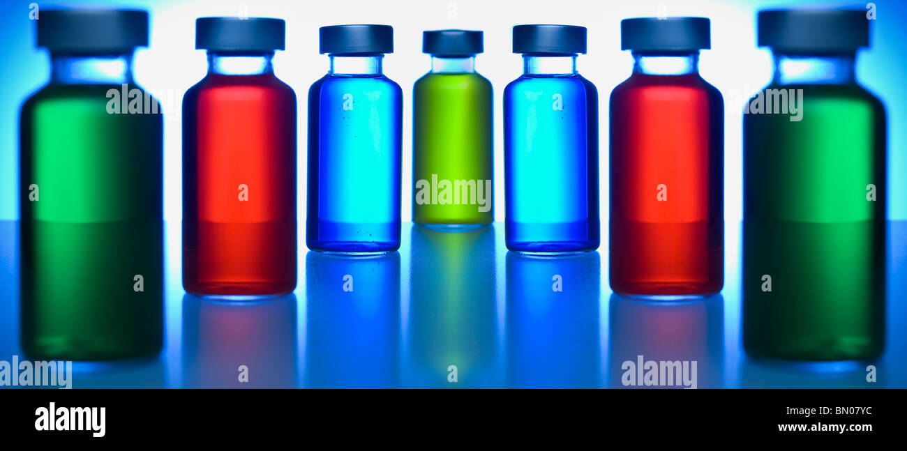 Two rows of vials filled with colored liquids. Focus on the blue ones. Stock Photo