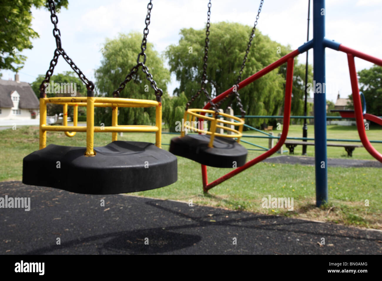 Empty swings in a child's playground, movement on one swing Stock Photo
